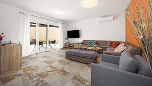 A modern living room with a sofa, ottoman, coffee table, and a TV mounted on the wall. - Luxe villa in Pula with pool and jacuzzi (Pula)