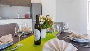 A dining table set with plates, glasses, a bottle of wine, and a vase of flowers.