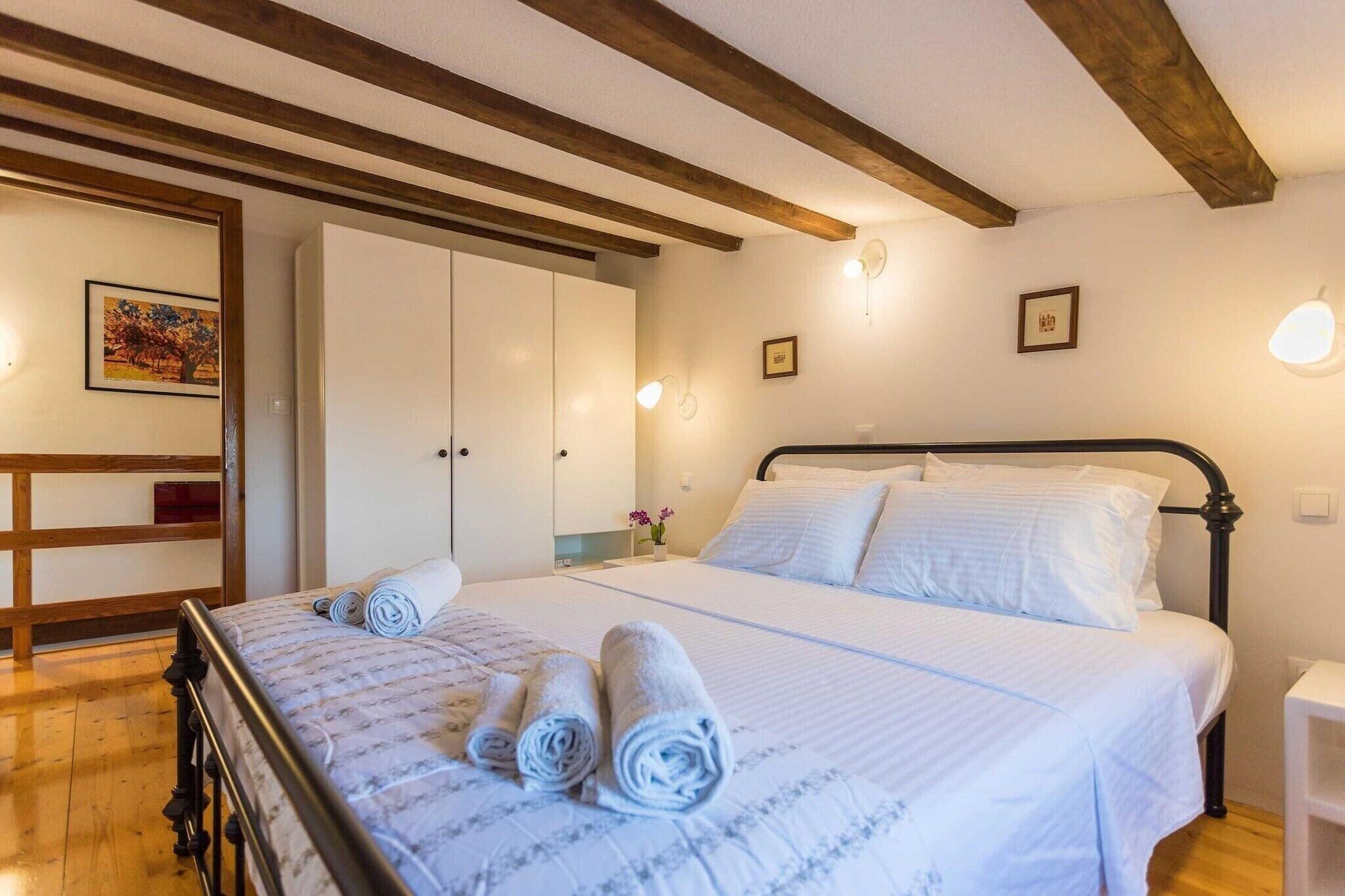 A hotel room with a bed, a wardrobe, and a small table with a lamp.