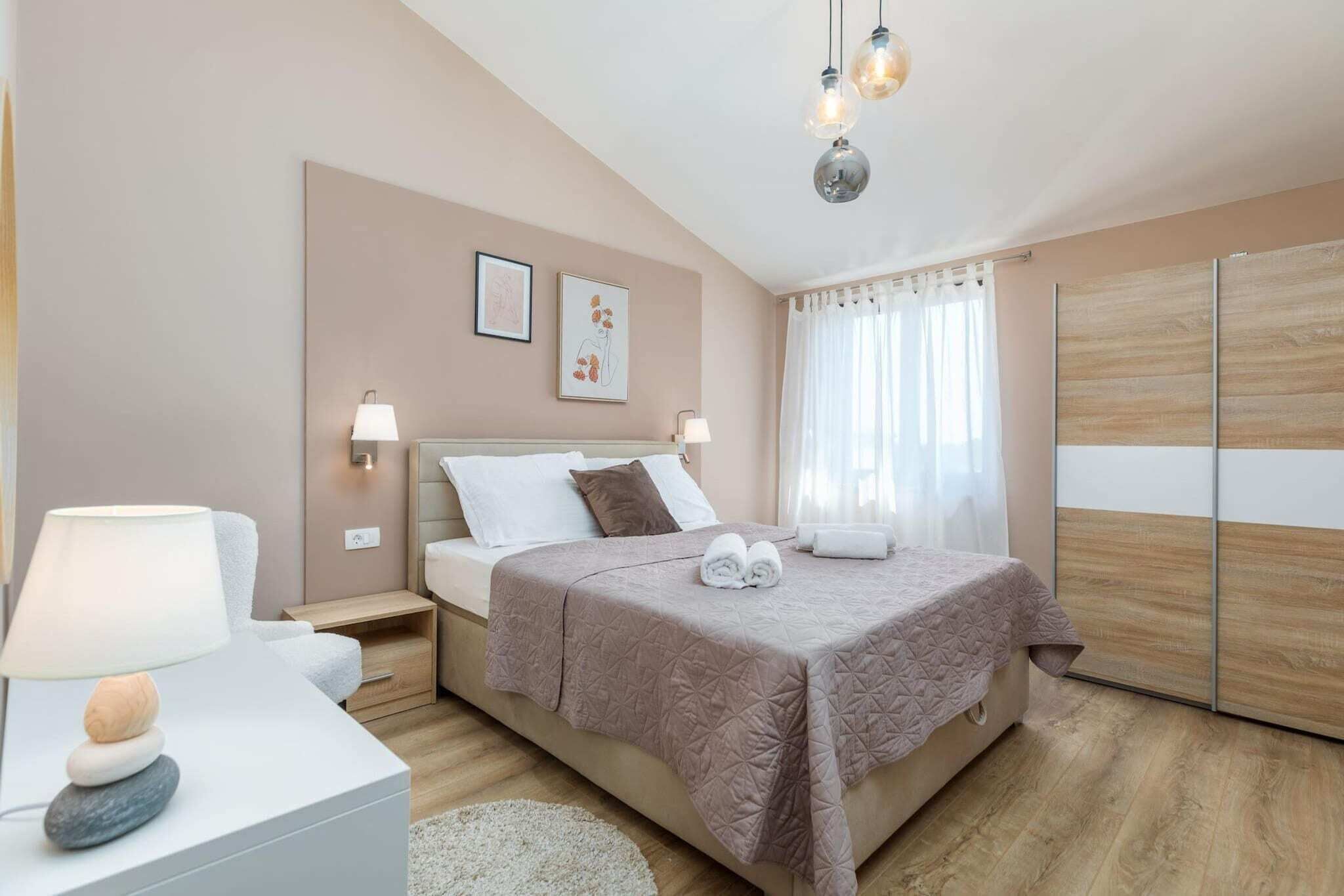 Un dormitorio ordenado con cama, lámparas de noche, mesita de noche y estante en la pared.