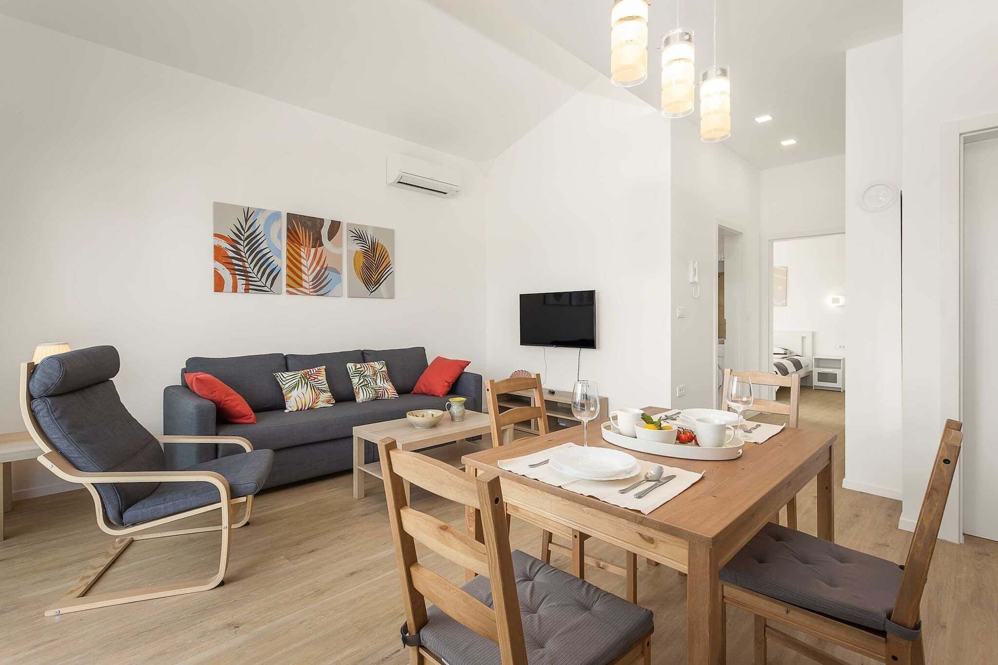 A modern living room with a sofa, a dining table with chairs, and artwork on the wall.