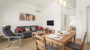 Un salon moderne avec un canapé, une table à manger et des chaises, ainsi que des œuvres d’art accrochées au mur.