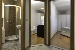 Ein modernes Badezimmer mit einer gläsernen Duschkabine, einem weißen Waschbecken und Holzboden.