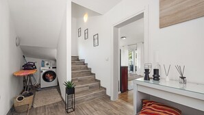 A modern interior with a staircase, a washing machine, a small table with a plant, and a glass shelf with candles. - Modern Rscape with Pool (Baderna)
