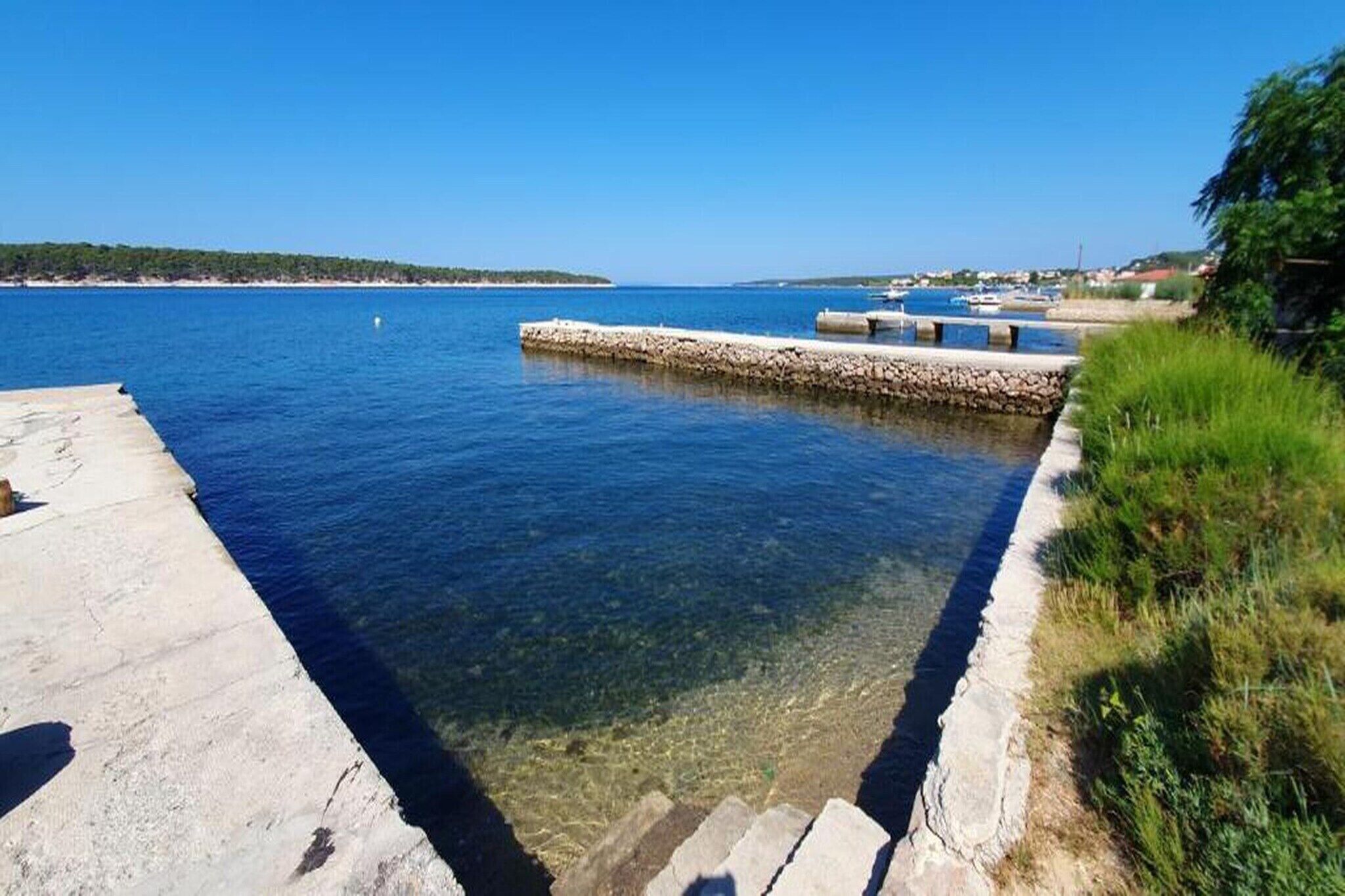 A clear waterfront with a stone pier and steps leading into the water.