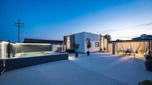 A modern outdoor patio area with a hot tub, seating, and potted plants.