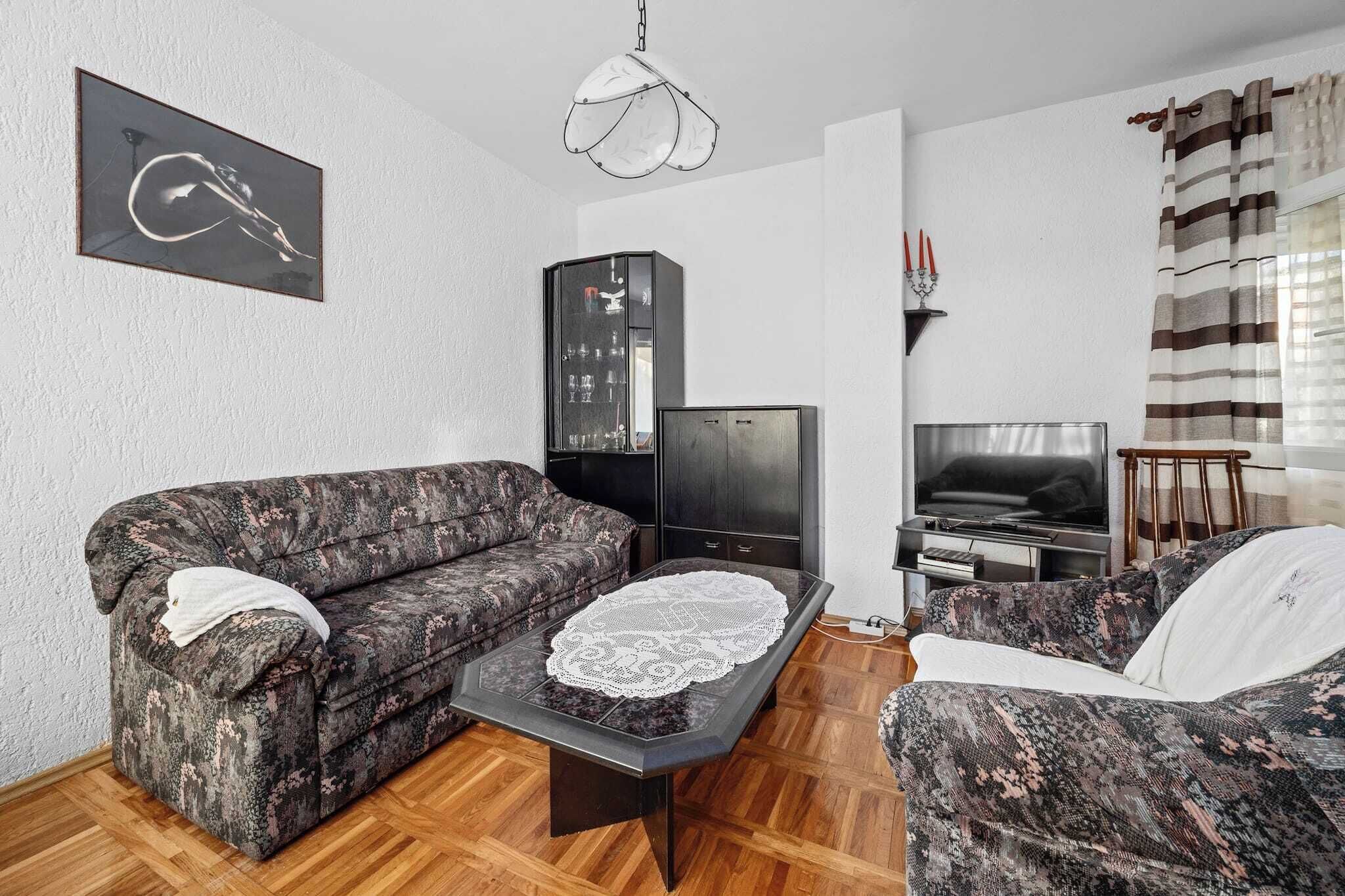 A living room with a sofa, a coffee table with a lace doily, a television, and a cabinet.