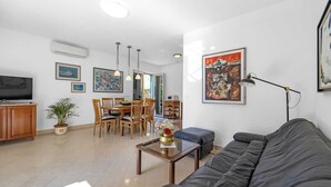 A modern living room with a sofa, a coffee table, a TV, and a dining area with chairs and a table. - Tranquil Escape in Banjol (Banjol)