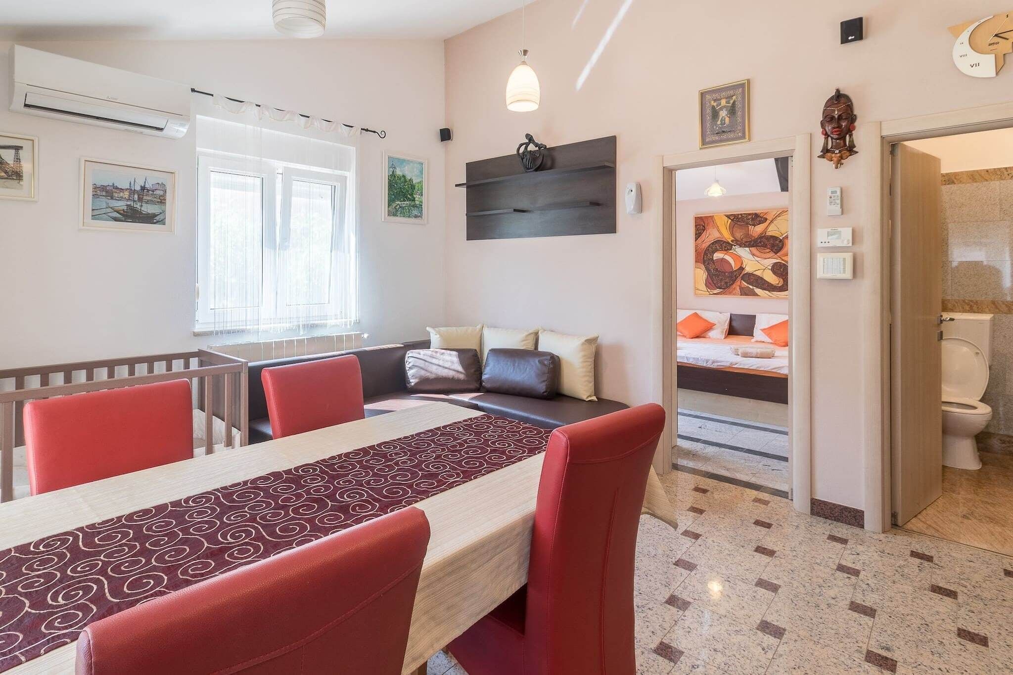 A modern hotel room with a dining area, a sofa, a bed, and a bathroom.