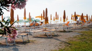 A beach with rows of sun loungers and umbrellas, some occupied, others empty. - House in Fažana near Rock Beach (Fažana)