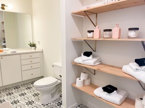 A bathroom with a toilet, shelves with towels and toiletries, and a mirror. - 🌄 5★ Downtown Retreat | Mtn Views & Pet Friendly (Chattanooga)