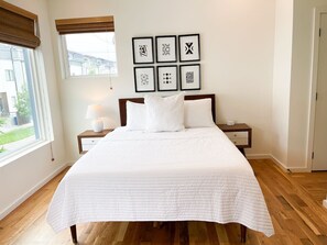 A neatly made bed with white bedding in a room with wooden flooring, a window with blinds, and a bedside table with a lamp. - 🌄 5★ Downtown Retreat | Mtn Views & Pet Friendly (Chattanooga)