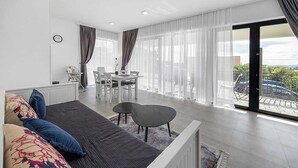 Un salon moderne avec un canapé, une table à manger et des chaises. Il y a un balcon avec vue sur la ville.