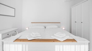Une chambre à coucher moderne avec un grand lit, des murs blancs et une tête de lit en bois.