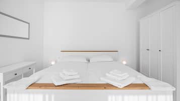 Ein modernes Schlafzimmer mit einem großen Bett, weißen Wänden und einem hölzernen Kopfteil.