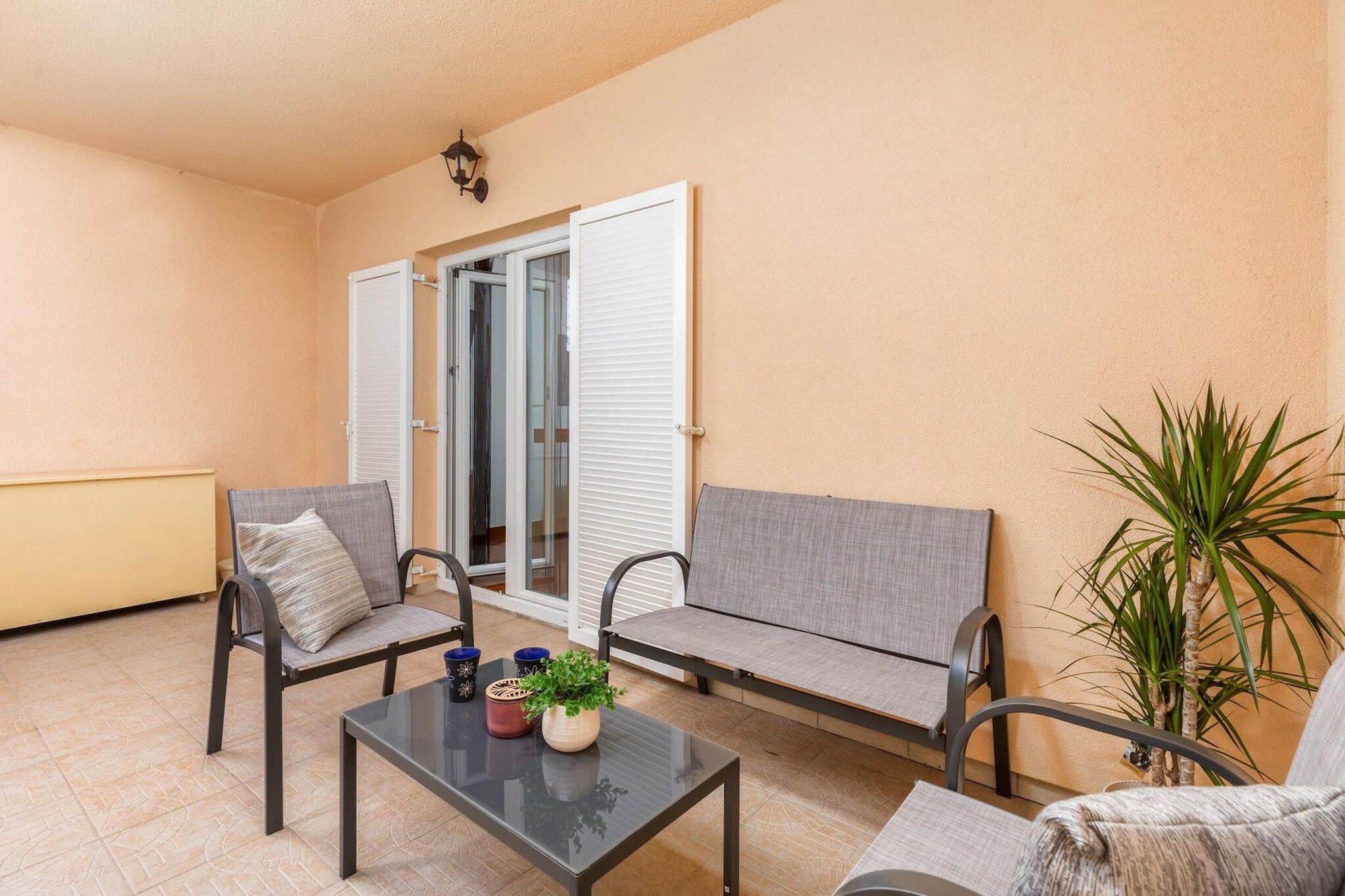 A balcony with two chairs, a table, and a potted plant.