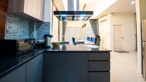 A modern kitchen with a central island, a built-in stove, and a large range hood. - Level Flow pool villa Pattaya (Sattahip)