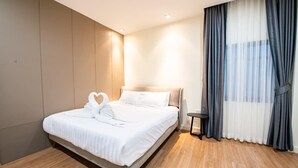 A neatly made bed with a swan-shaped pillow decoration, a bedside table, and a large window with sheer curtains. - Level Flow pool villa Pattaya (Sattahip)