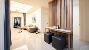 A modern living room with a sofa, ottomans, a wooden partition, and a dining table. - Level Flow pool villa Pattaya (Sattahip)