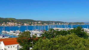 A marina with multiple sailboats docked, surrounded by lush greenery and a clear blue sky. - Apartment in Supetarska Draga near Sandy Beach (Supetarska Draga)