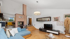 A modern living room with a blue sofa, a glass coffee table, a flat-screen TV, and a fireplace.