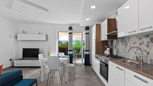 A modern kitchen with white cabinets, a built-in stove, and a tiled backsplash.