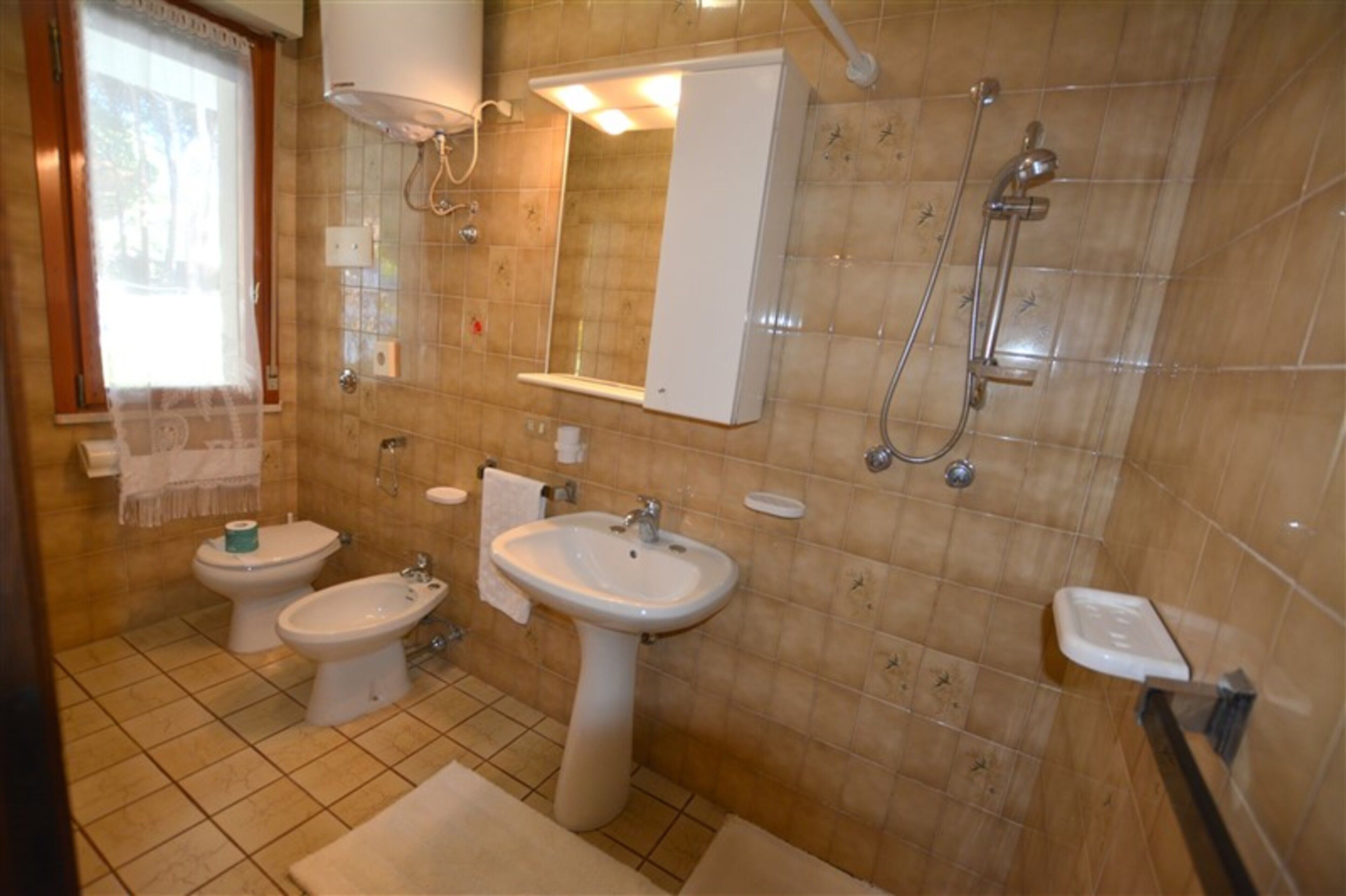 A bathroom with a toilet, bidet, sink, and shower.