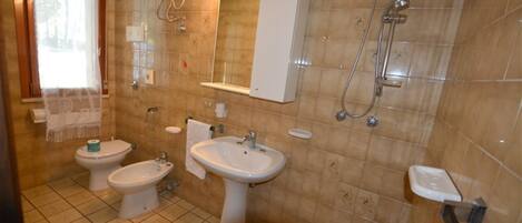 A bathroom with a toilet, bidet, sink, and shower.