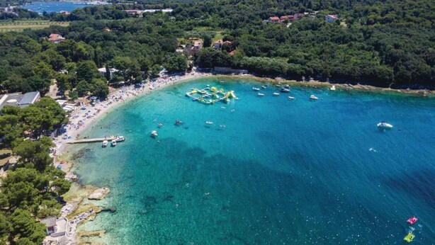 An aerial view of a coastal area with a beach, boats, and a forested area in the background. - Apartment in Pula near City Center Waterfront (Pula)