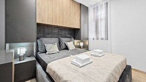 A modern bedroom with a bed, bedside tables, and a nightstand. - Apartment in Pula near City Center Waterfront (Pula)