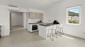 A modern kitchen with white cabinetry, a built-in oven, a microwave, and a large island with bar stools.