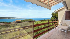 A balcony with a view of the sea, a chair, and a striped awning. - Apartment in Supetarska Draga near Sandy Beach (Supetarska Draga)