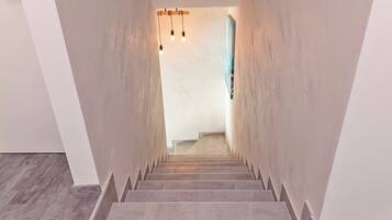 A staircase with a modern design, leading to a room with a light-colored wall and a wooden floor.