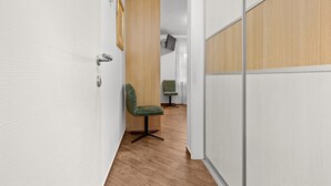 A hallway with a wooden door, a green upholstered chair, and a small table with a television. - Villa Pineta two bedroom apartment (Medulin)