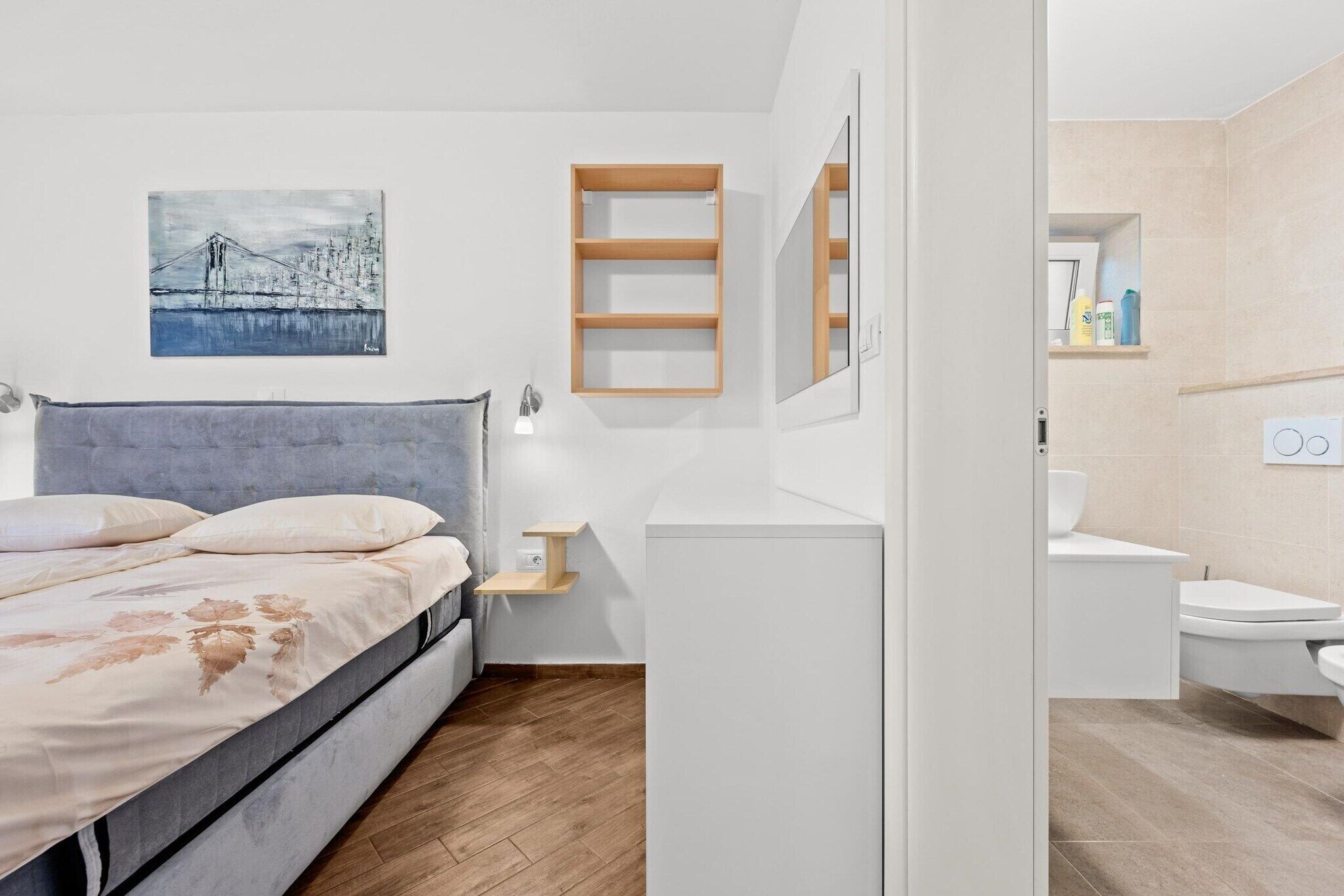 Een moderne slaapkamer met een bed, nachtkastje en een wandplank.