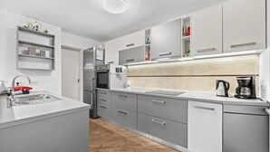 A modern kitchen with grey cabinetry, a stainless steel refrigerator, an oven, and a coffee maker. - Villa Pineta two bedroom apartment (Medulin)