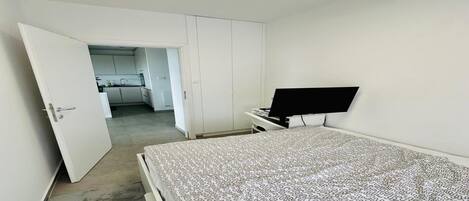 A bedroom with a bed, a TV on a stand, and a wardrobe.