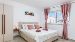 A bedroom with a bed, a nightstand, a painting, and a window with curtains. - Lovely family bungalow with private pool (Valbandon)