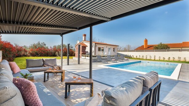A covered outdoor area with a pool, seating, and a view of a house. - Lovely family bungalow with private pool (Valbandon)