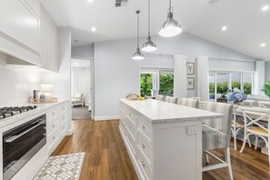 A modern kitchen with a central island, wooden flooring, and pendant lighting. - BLUE GUM ESCAPE - THE VINTAGE HOLIDAY HOUSES (POKOLBIN)