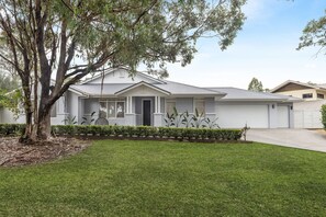 A single-story house with a front porch, a garage, and a well-maintained lawn. - BLUE GUM ESCAPE - THE VINTAGE HOLIDAY HOUSES (POKOLBIN)