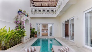 A pool area with lounge chairs and a view of the interior.