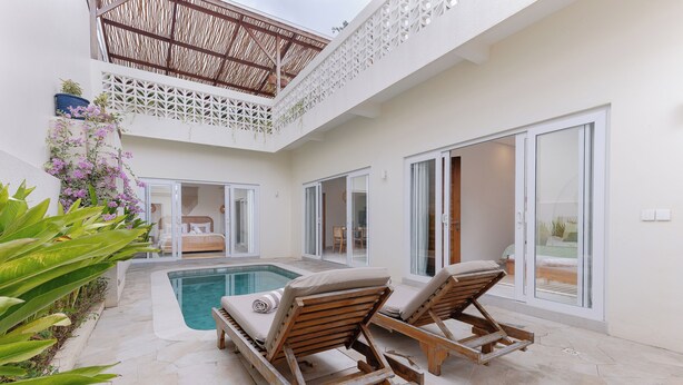 A poolside area with lounge chairs, a swimming pool, and a covered patio.