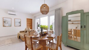 A dining area with a round table, wooden chairs, and a hanging light fixture.