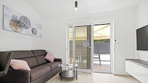 A modern living room with a sofa, a coffee table, and a large abstract painting. - Apartment, 100m from the beach (Peroj)