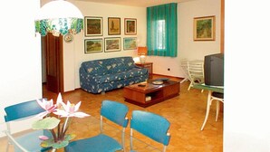 A living room with a sofa, chairs, a coffee table, a television, and framed pictures on the wall. - Ground floor vacation home for six guests (Lignano Sabbiadoro)