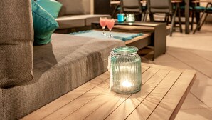 A cozy living area with a sofa, a coffee table with a lit candle, and a glass jar.