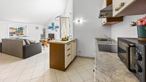 A modern apartment with a kitchenette, a dining area, and a living room with a sofa.
