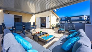 A covered outdoor seating area with sofas, chairs, and a coffee table.