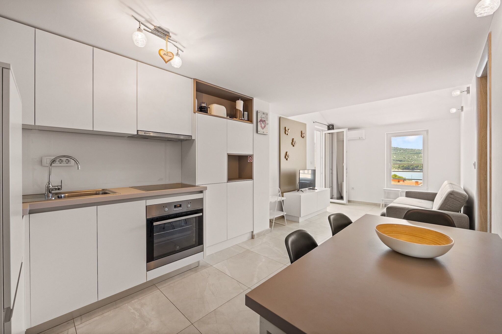 Una cucina moderna con mobili bianchi, forno integrato e zona pranzo con tavolo e sedie.